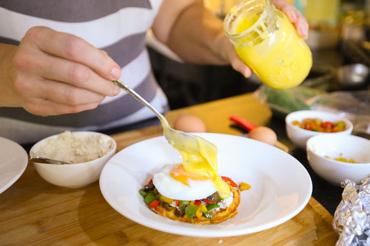 Keto eggs benedict made at The Larder — a poached egg on a carnivore waffle (chaffle) with sautéed peppers, topped with our hollandaise sauce being spooned from a glass jar