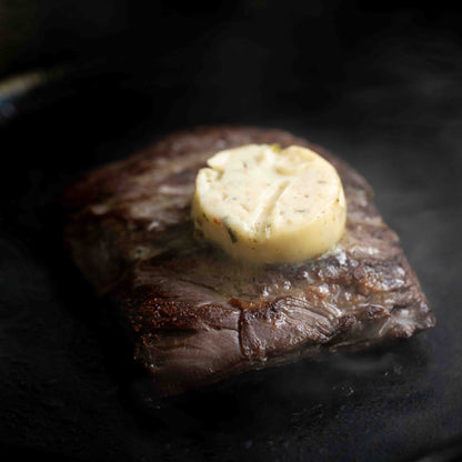 Grilled steak with a pat of butter on a cast iron pan