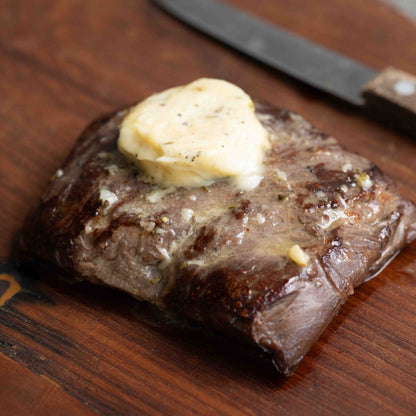 Tenderloin steak with a pat of garlic confit and rosemary butter on a wooden cutting board